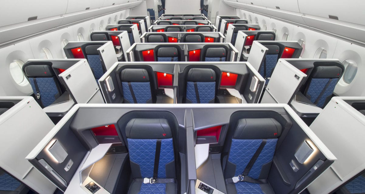 delta business class cabin with enclosed suites and blue leather seats with red and white accents