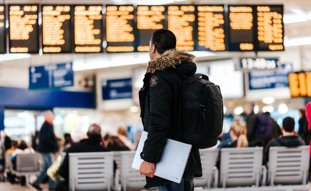 Traveler with a backpack looking at flight departure board.