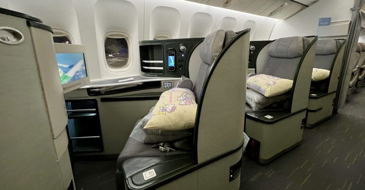 eva air business class seat with light yellow pillows on the seat inside an egshell-colored seat shell and black interior finishes.