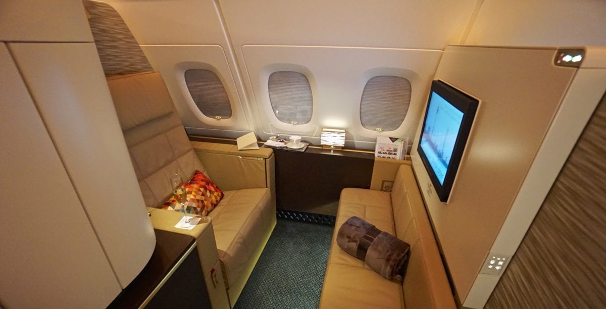The interior of the Etihad Apartment, featuring a big recliner chair, a bench, and a TV screen.