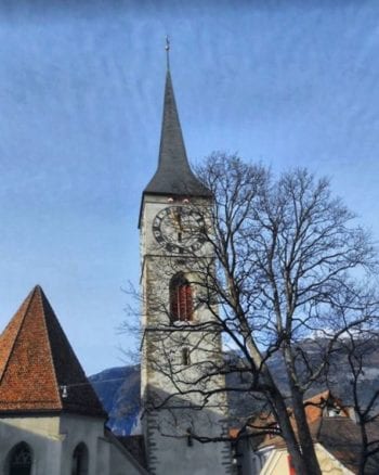 4 Small Towns in Switzerland You Need to Visit 3 A large church tower with a clock on the side of a building