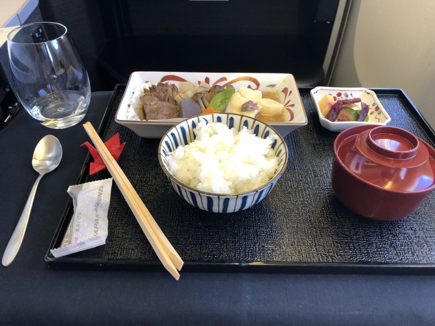 a tray with a bowl of rice, miso soup, pickles, and beef