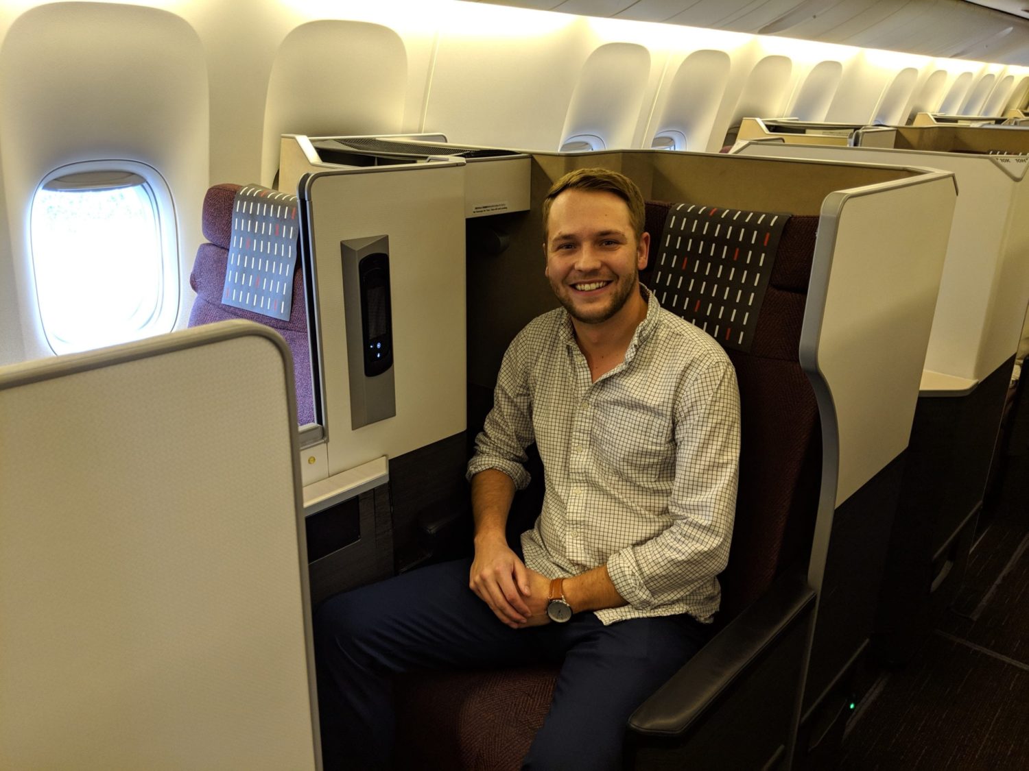 a man smiling while sitting inside a business class seat