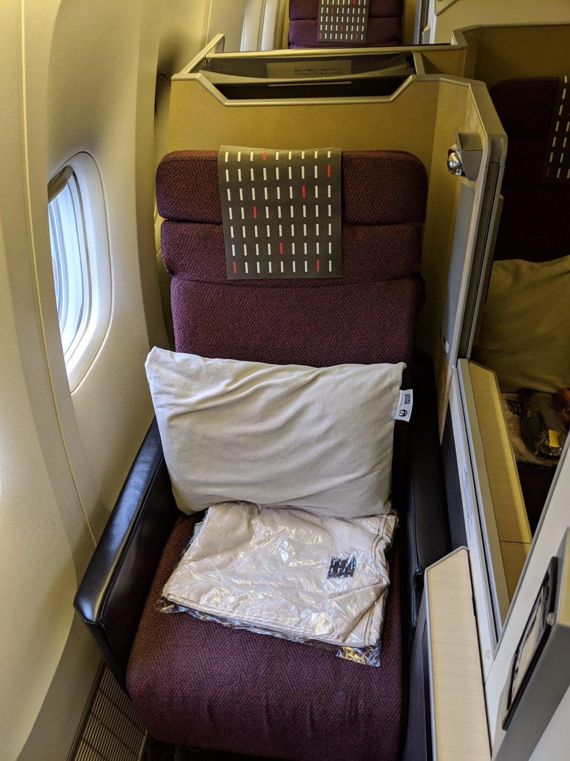 business class seat alongside the window of a plane with several windows open