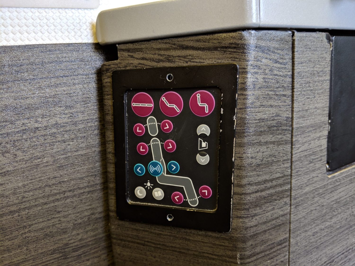 airline seat controls on a side panel inside of the plane