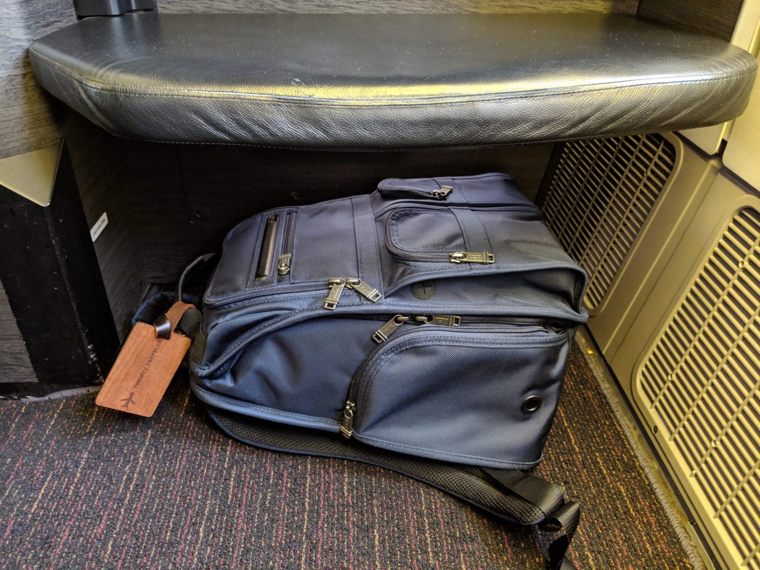 a backpack underneath an ottoman on a plane