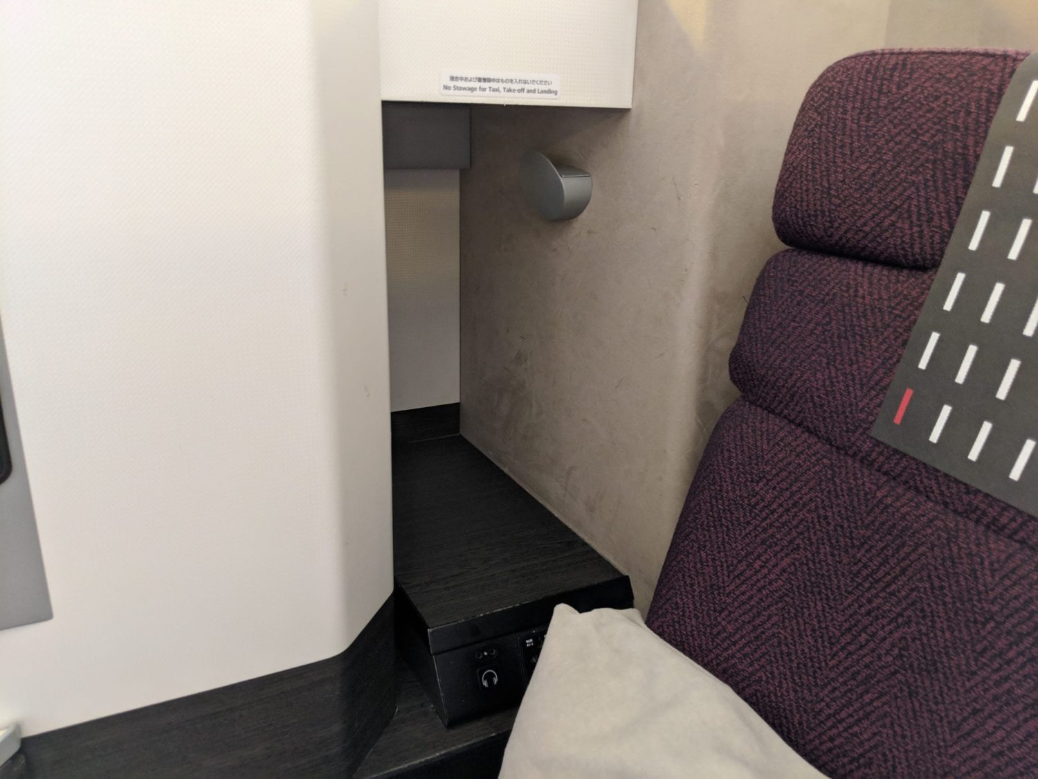 a small storage compartment with a hook for headphones inside of a business class suite