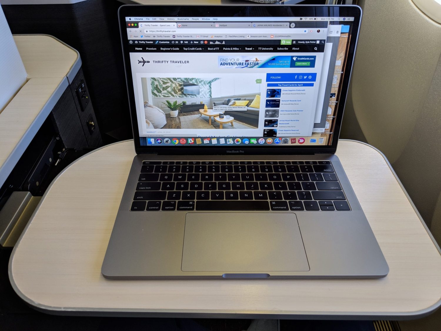 a macbook laptop sitting on an airplane tray table