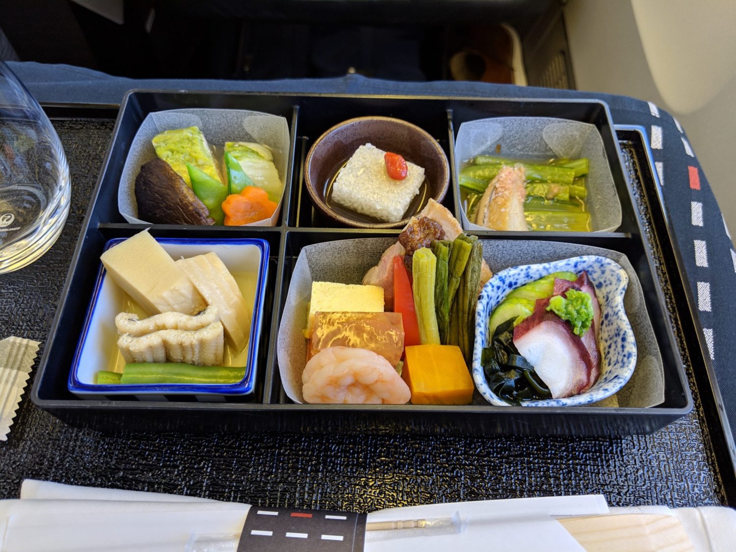 a rectangular tray with six small dishes of food