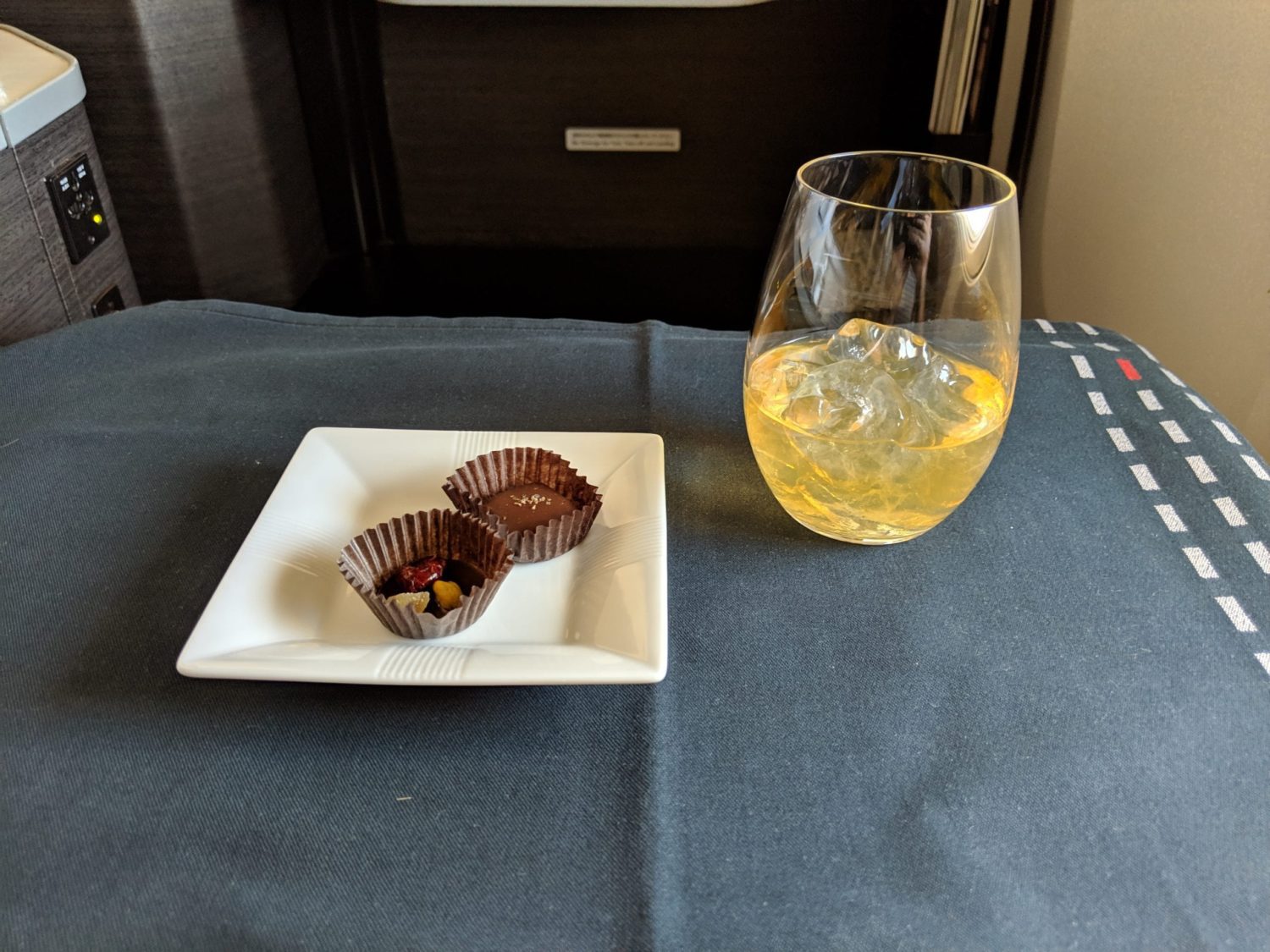 a glass of japanese whisky in ice near a plate with two chocolate truffles