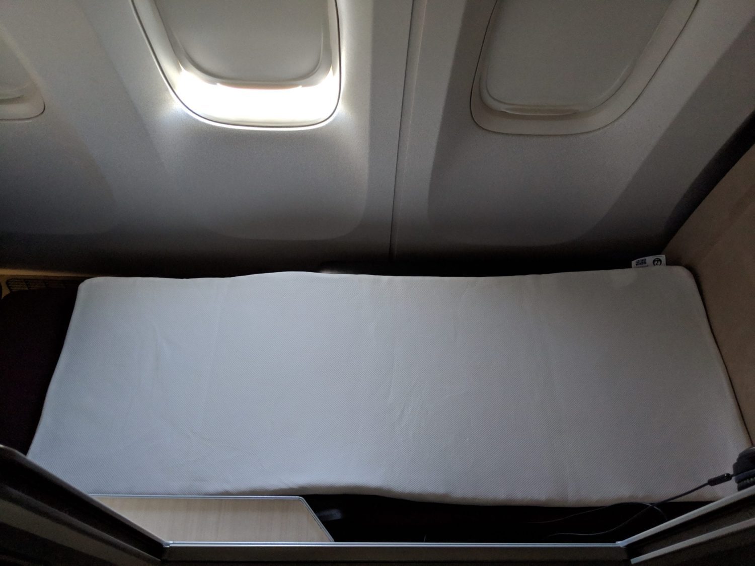 a mattress pad laying on a fully reclined business class seat