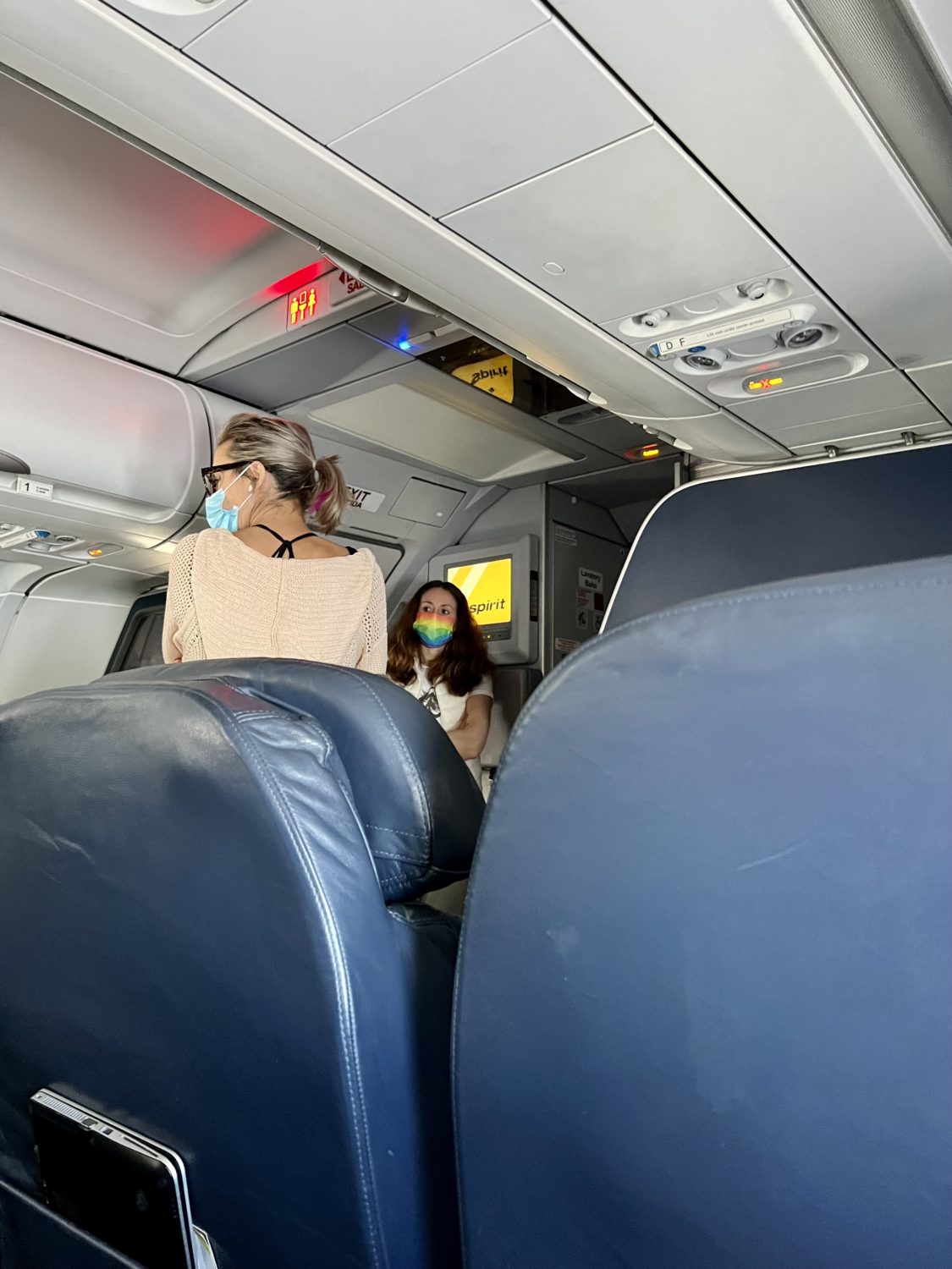 people standing in the front of a plane waiting to use the lavatory