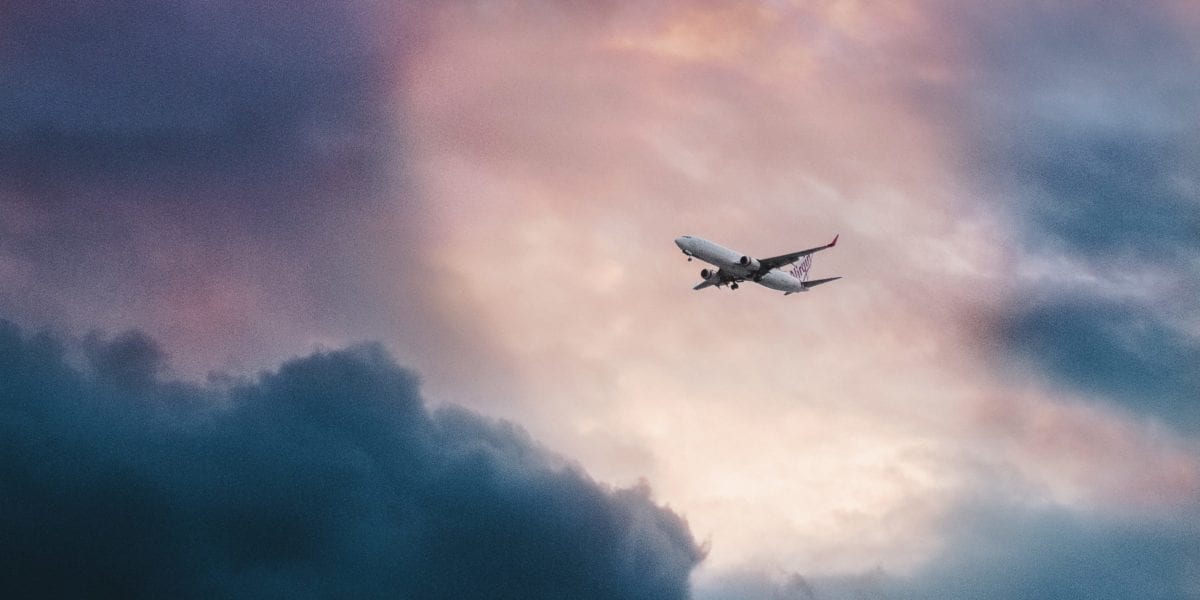 A large passenger jet flying through a cloudy blue sky