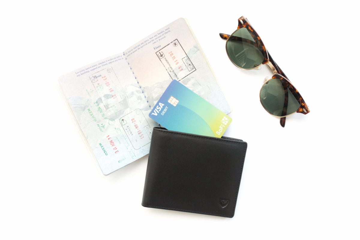 sofi money card with a wallet, passport and sunglasses