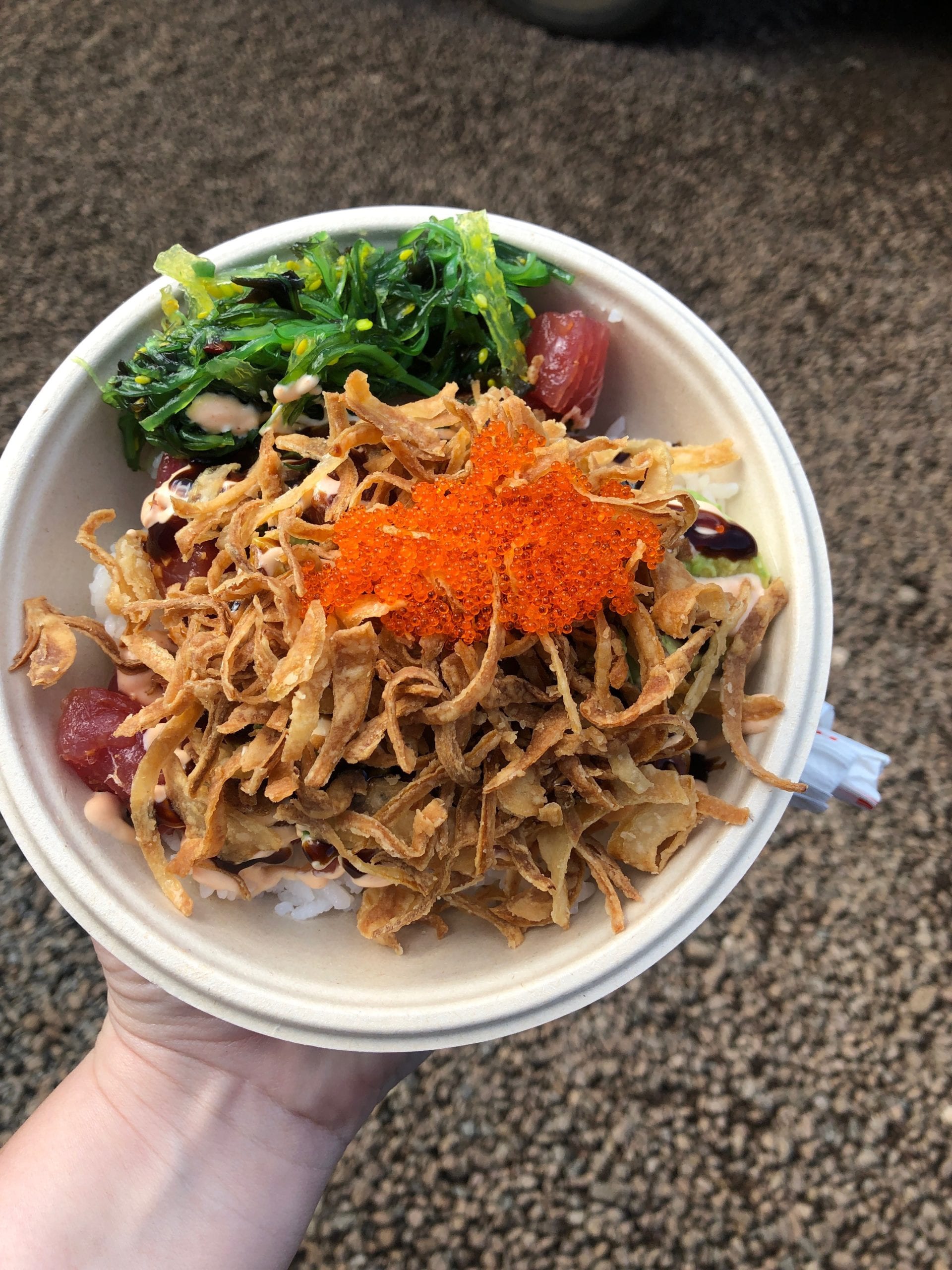 a bowl of poke with salmon roe, seaweed, and crispy onions