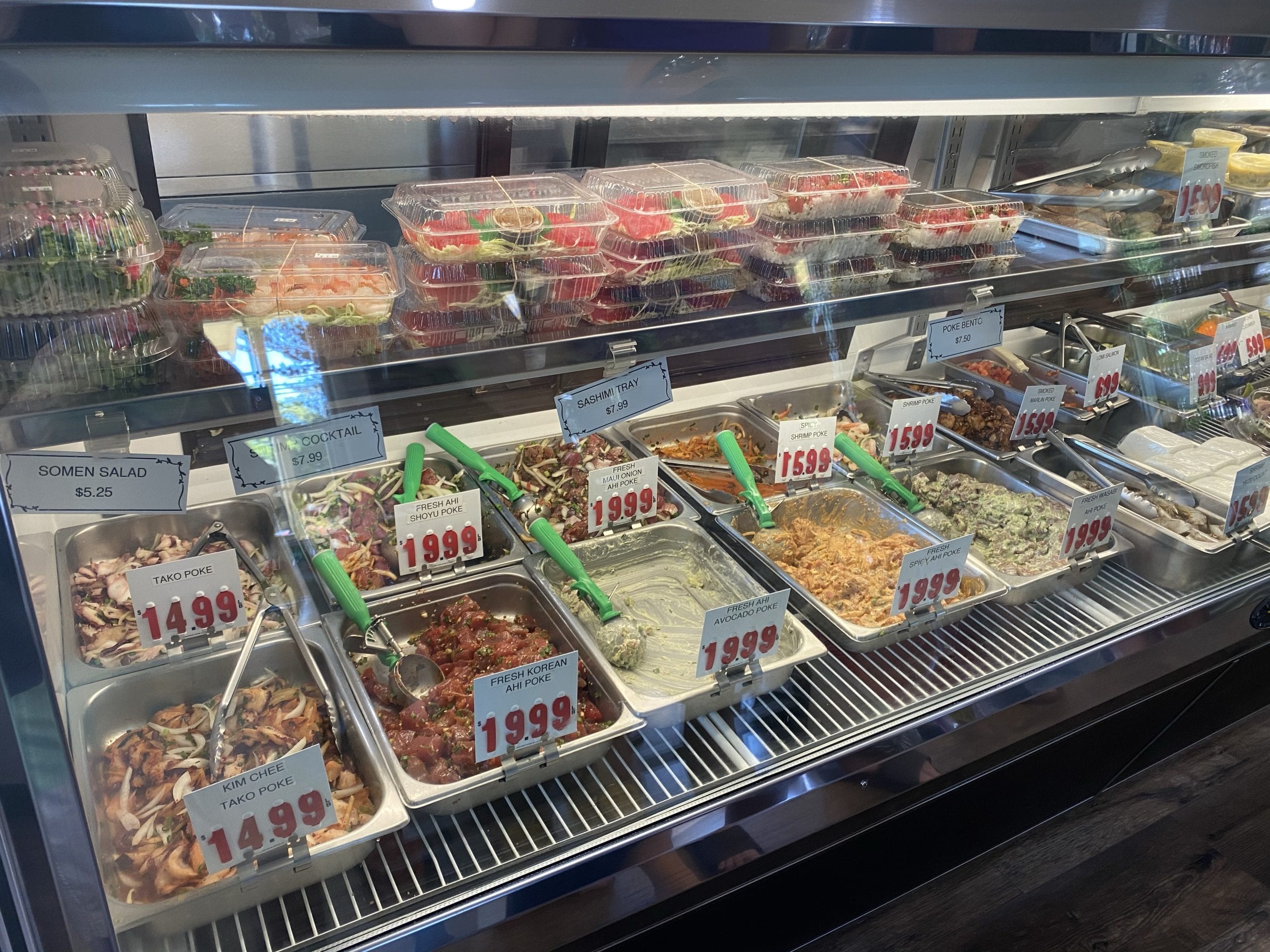 several containers of fish and other seafood with prices