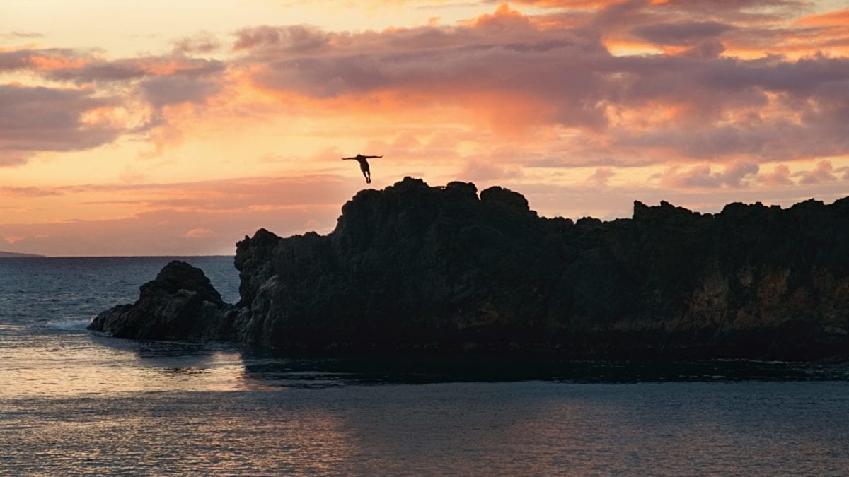 A sunset over a body of water with a mountain in the background