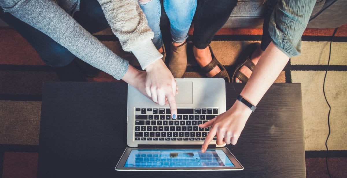 A person using a laptop computer sitting on top of a table