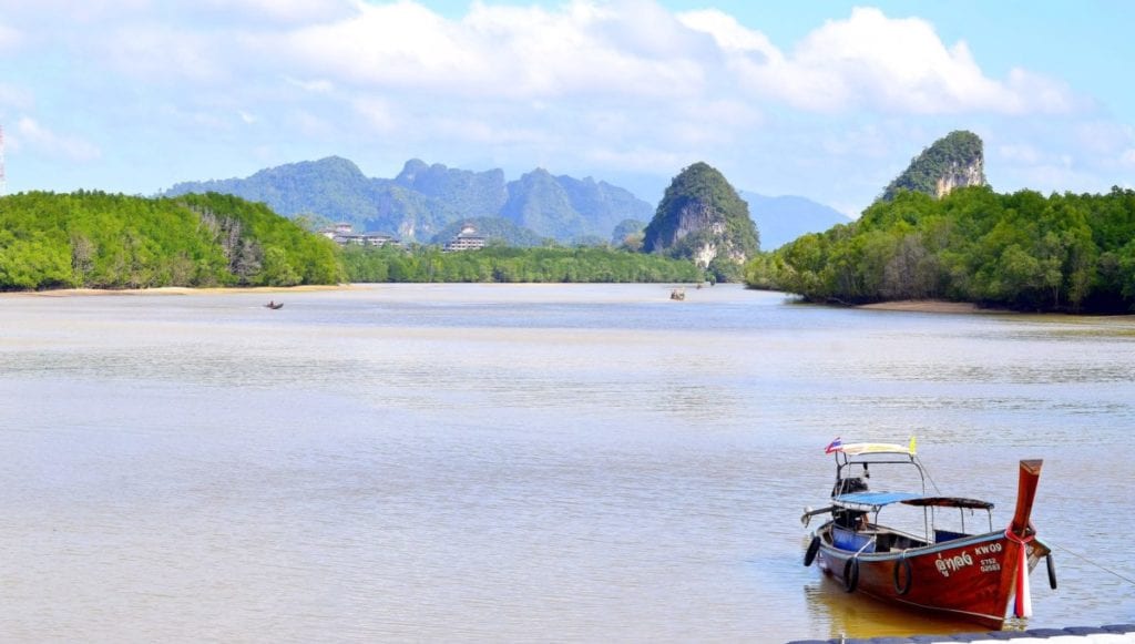 A boat floating along a body of water with Li River in the background