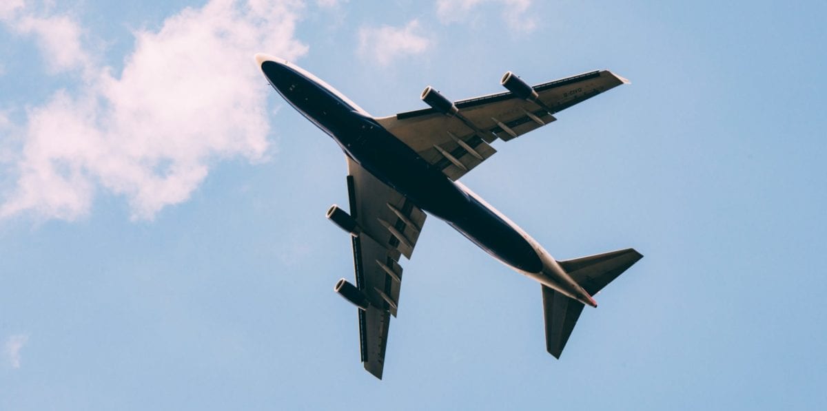 A commercial jet flying through a cloudy blue sky
