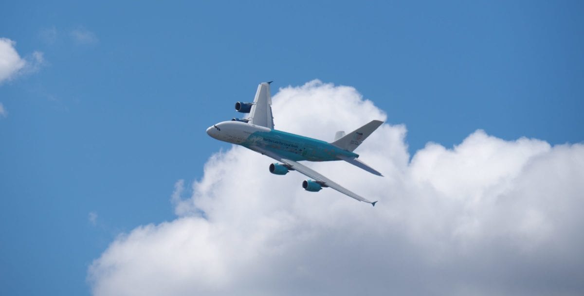 A large passenger jet flying through a cloudy blue sky