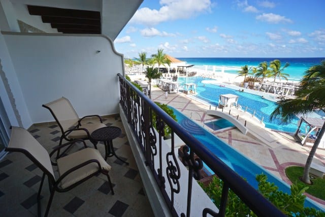a hotel room balcony overlooking a swimming pool and the ocean. 