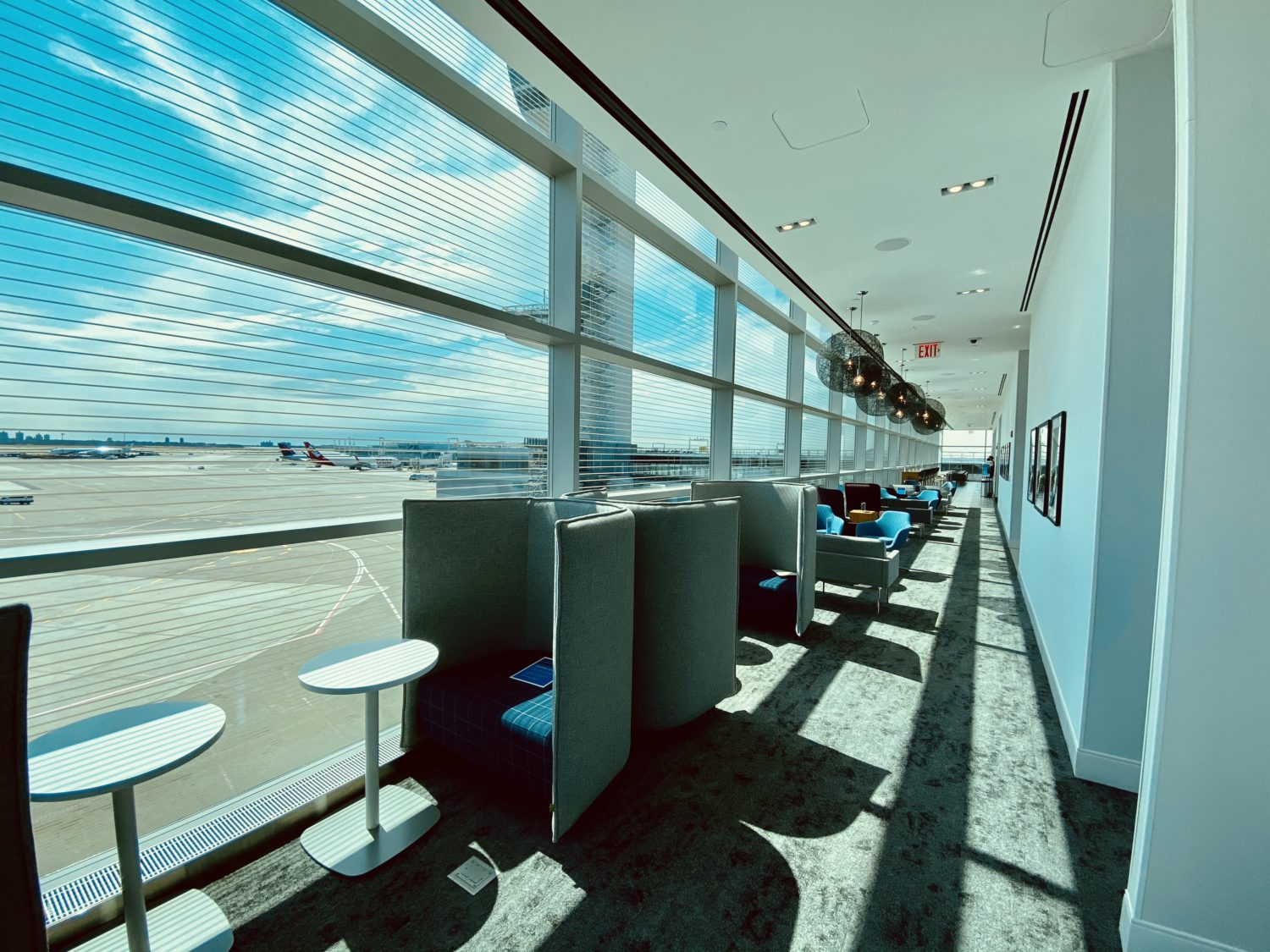 rows of seating next to windows inside an amex airport lounge