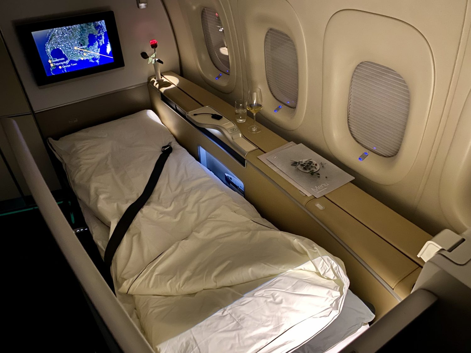 lufthansa first class bed with wine glasses and a flower