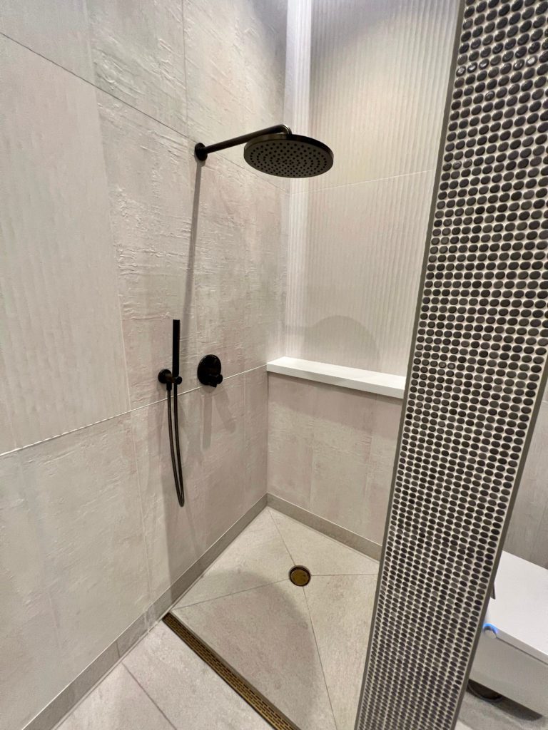 a shower with tile walls and a rain showerhead
