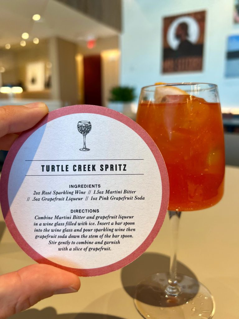 a shimmering drink in a wine glass with a cocktail coaster