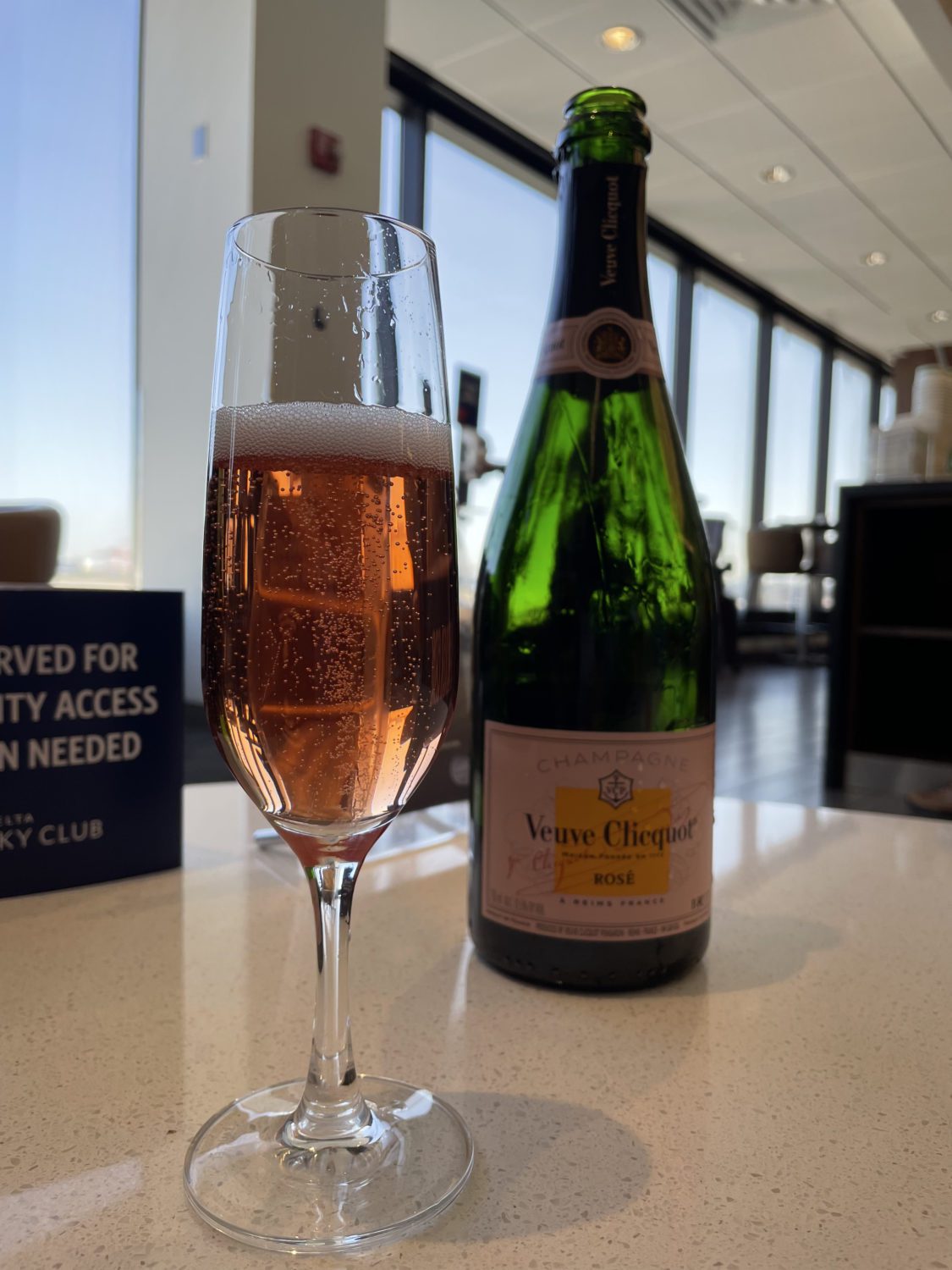 A bottle of veuve rose champagne and half full champagne glass