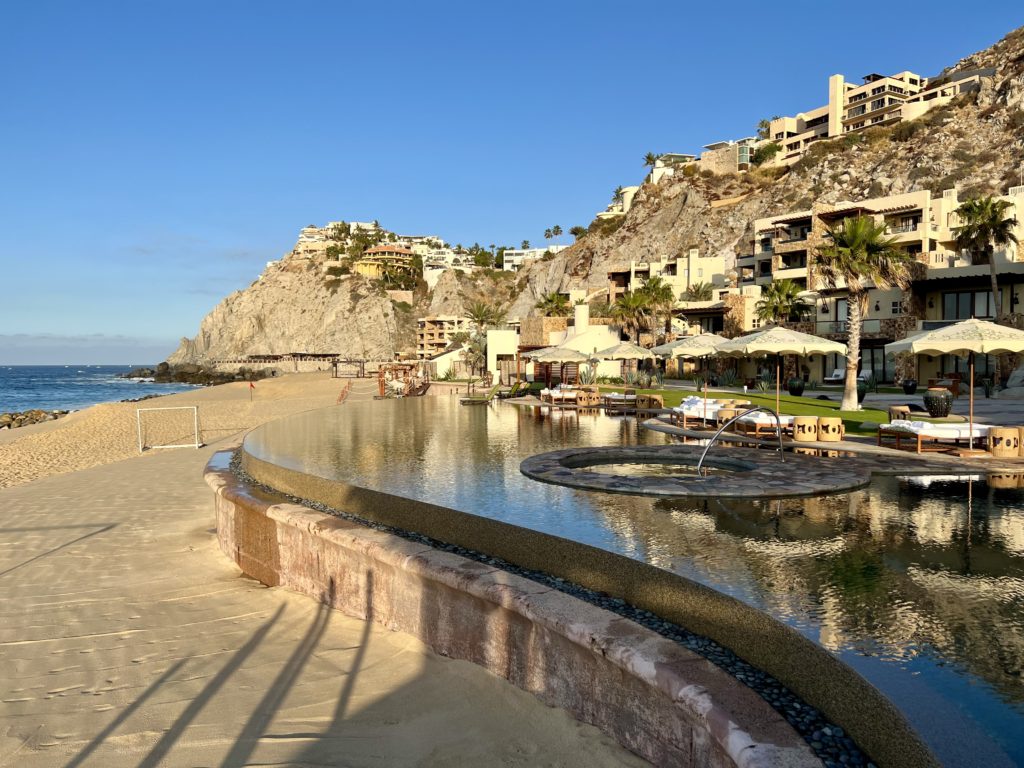 an infinity pool with hills and villas in the background