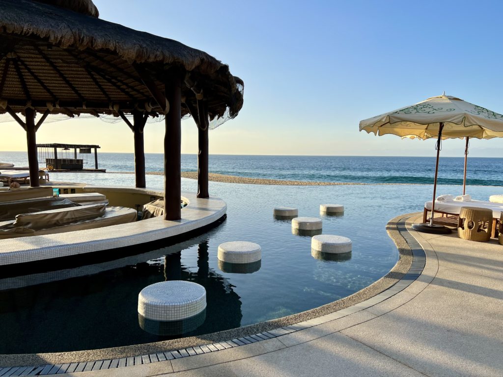 Luxury at its Finest: A Full Review of the Waldorf Astoria Los Cabos Pedregal 61 a swim up bar surrounded by small white stools