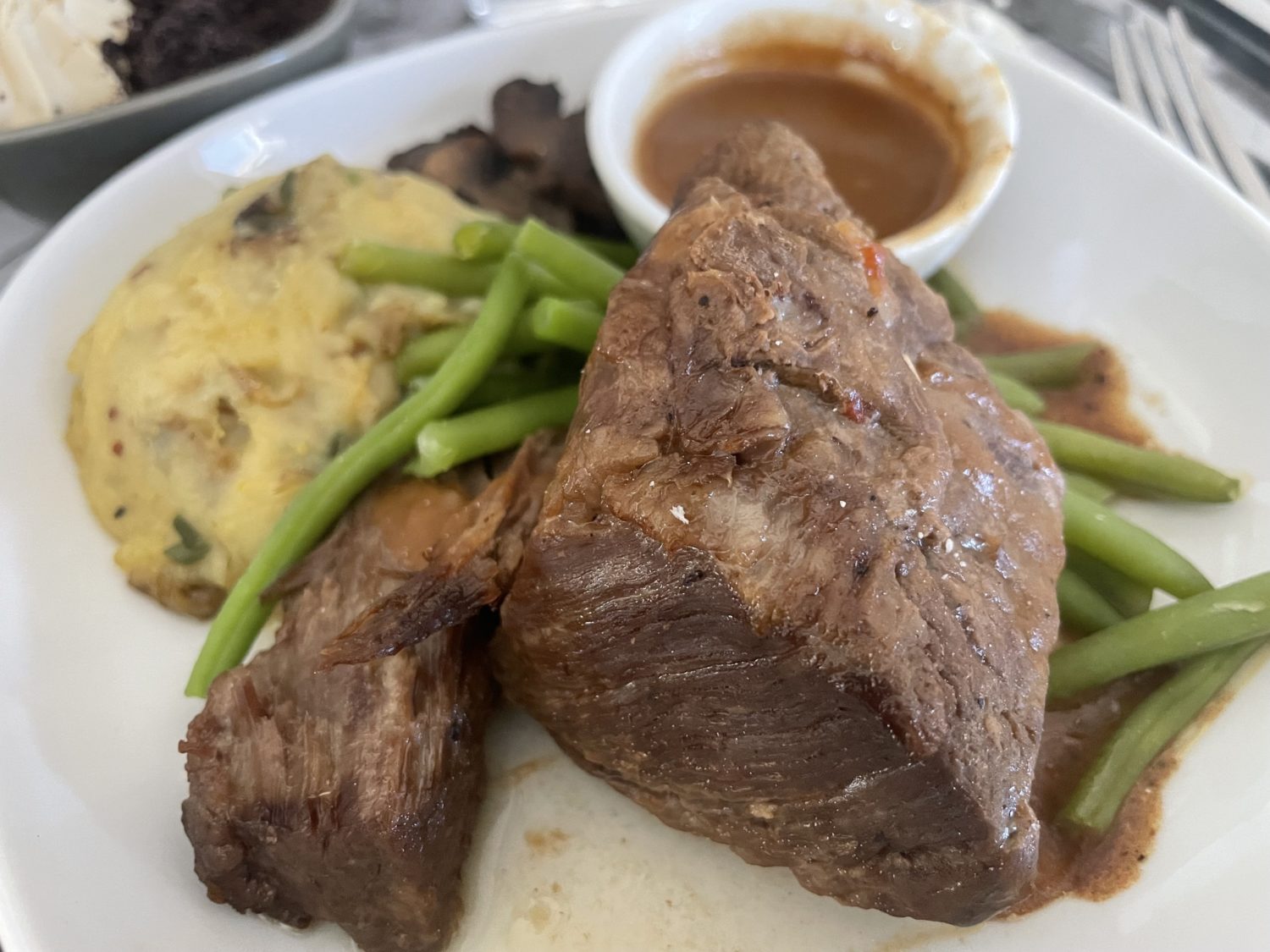 Short ribs on a plate with green beans and potatoes. 