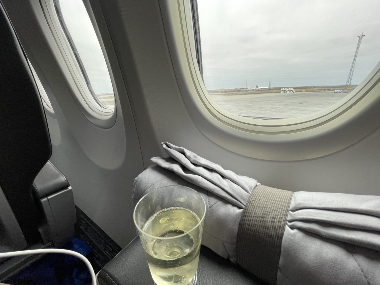 a glass of prosecco on the armrest next to the window on an airplane 