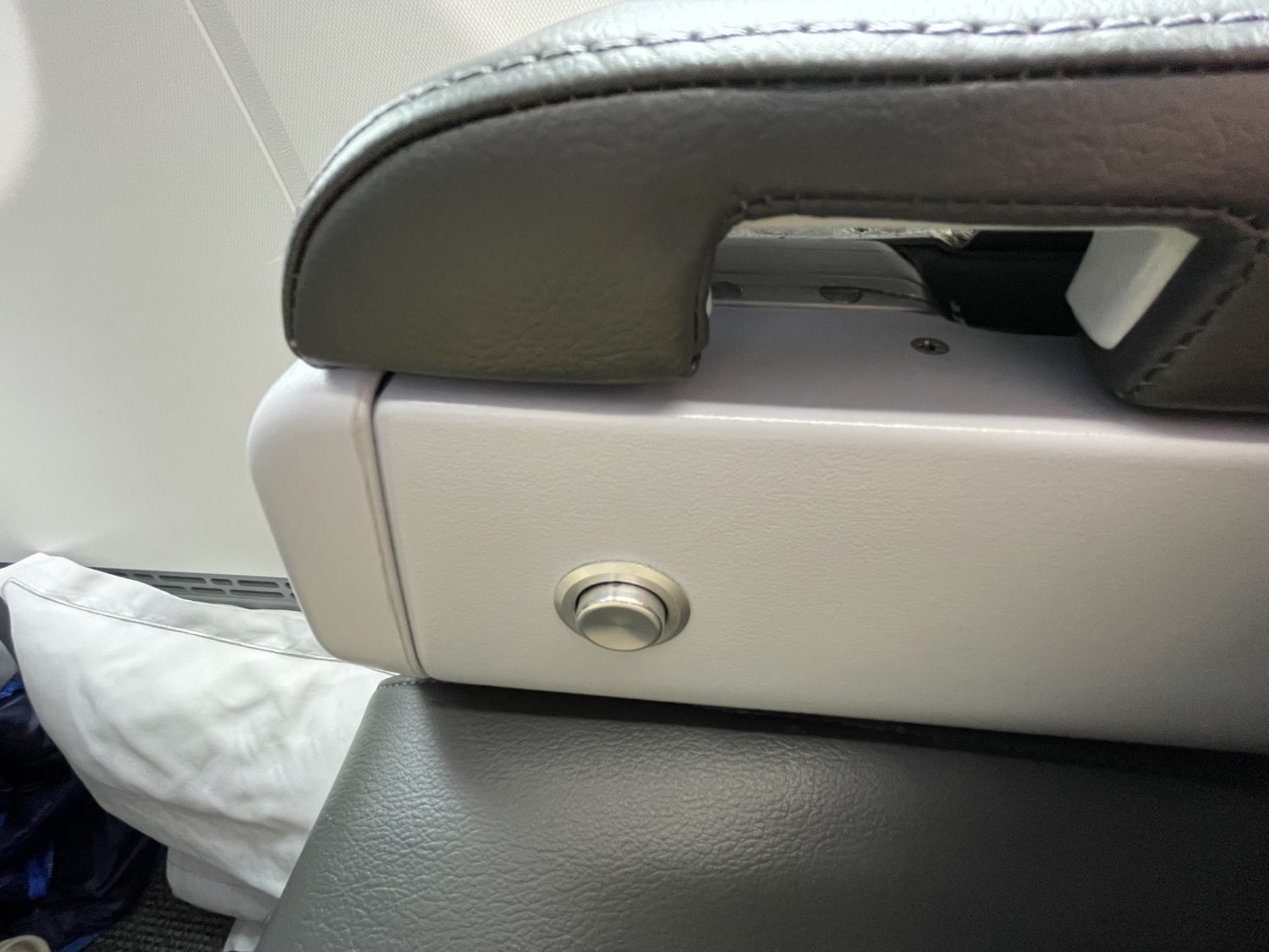 Recline button on an airplane seat. 
