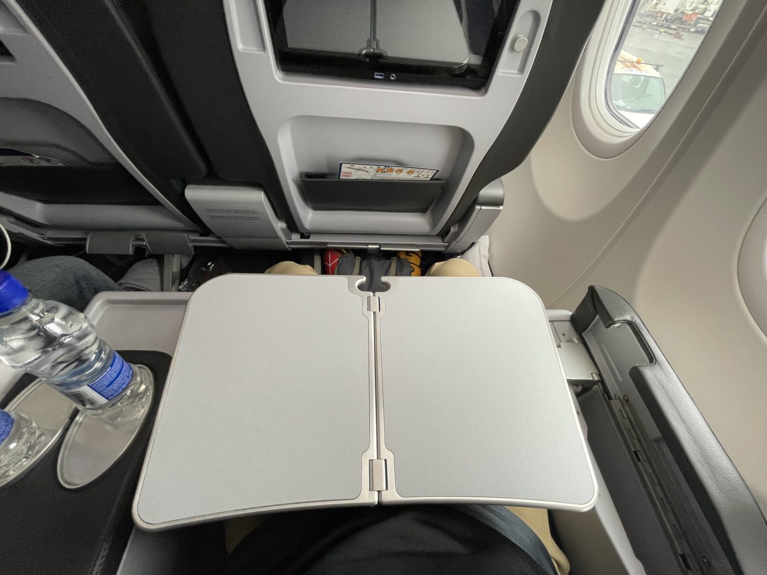 An empty tray table folded out over a passenger's lap. 