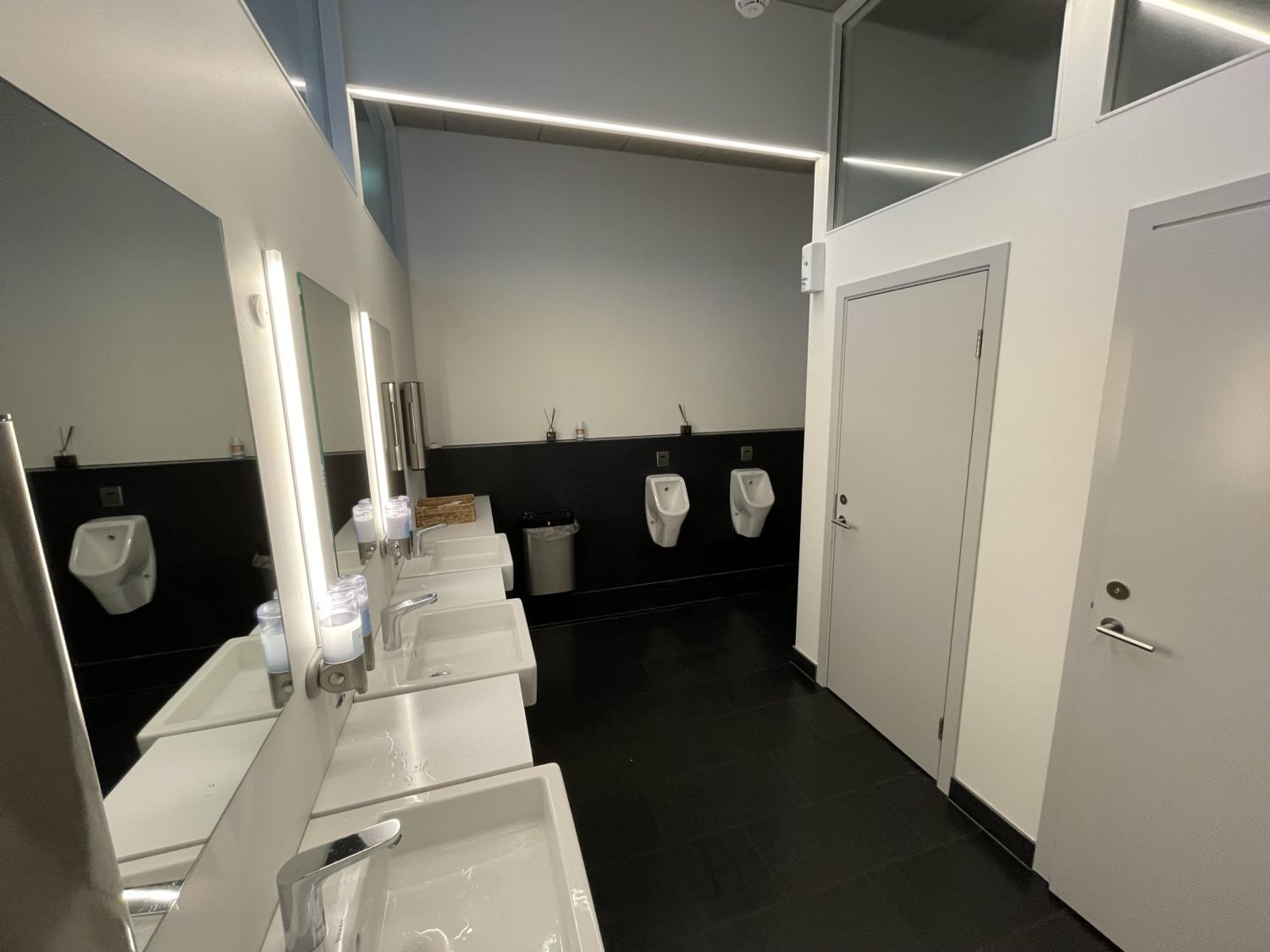 the men's bathroom with stalls, sinks and two urinals. 
