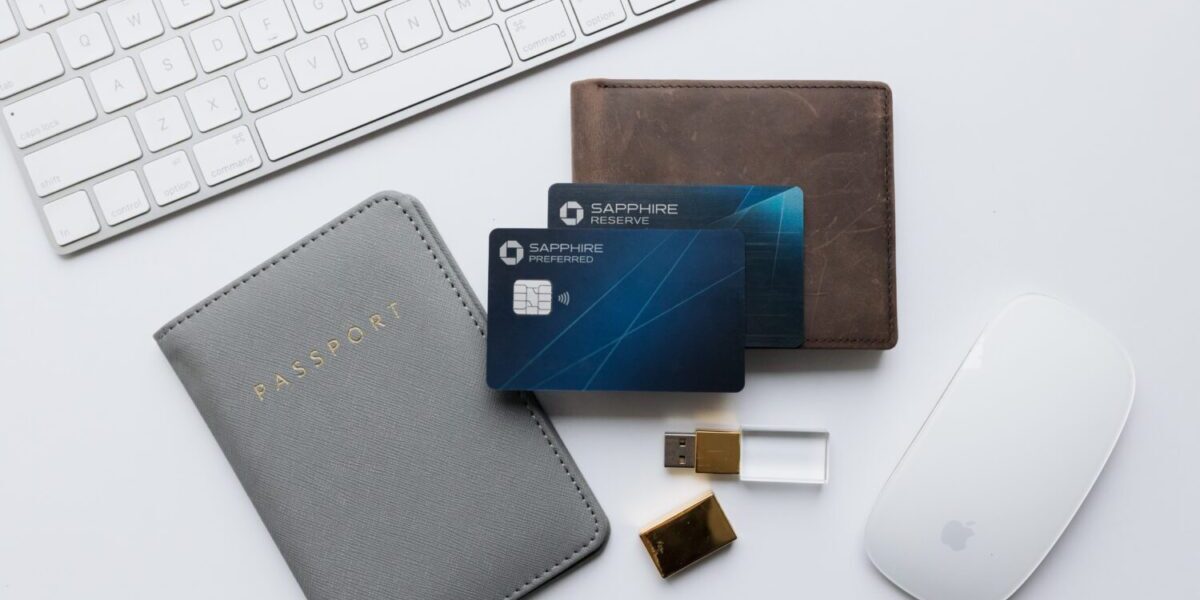 Chase Sapphire Preferred abd Reserve cards stacked on-top of a wallet, passport holder, USB drive, and Apple mouse and keyboard
