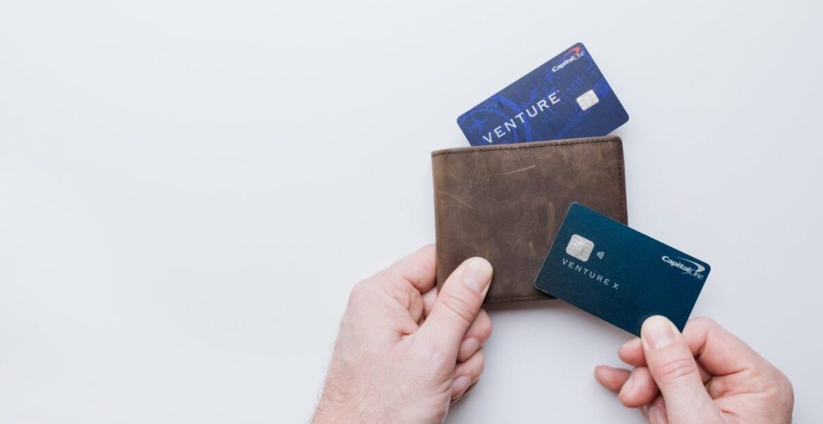 A hand holding a wallet with the Capital One Venture and Venture X credit cards.