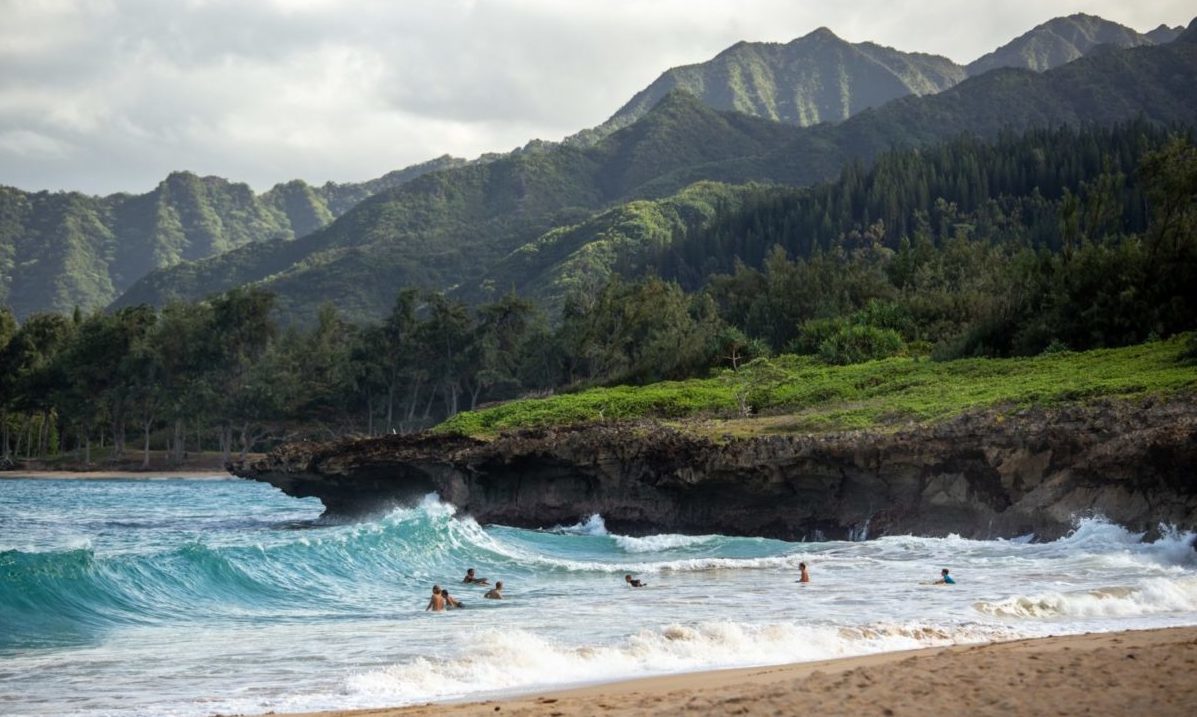 Resolved to Travel More in 2024? Here's How to Do it For Less 7 A beach with a mountain in the background