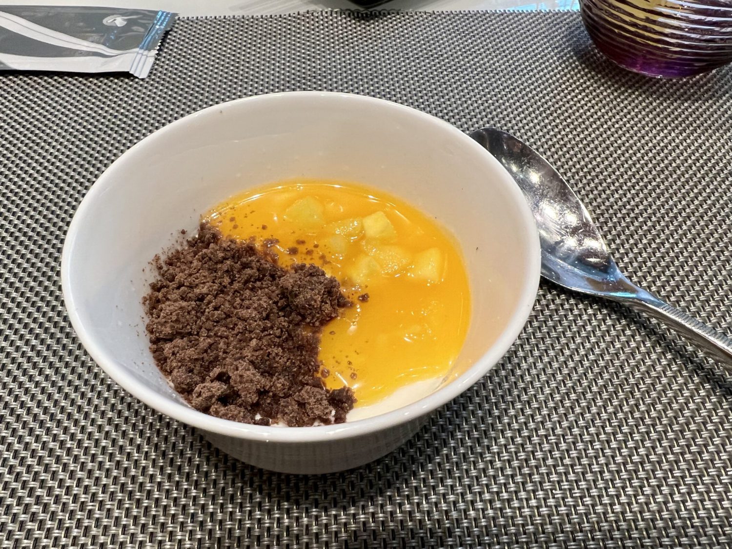 dish of panna cotta with mango and chocolate cookie crumble on a place mat