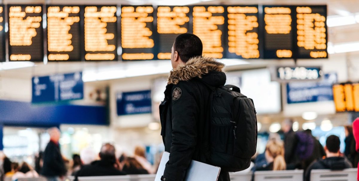 A person standing in front of an airport departures board