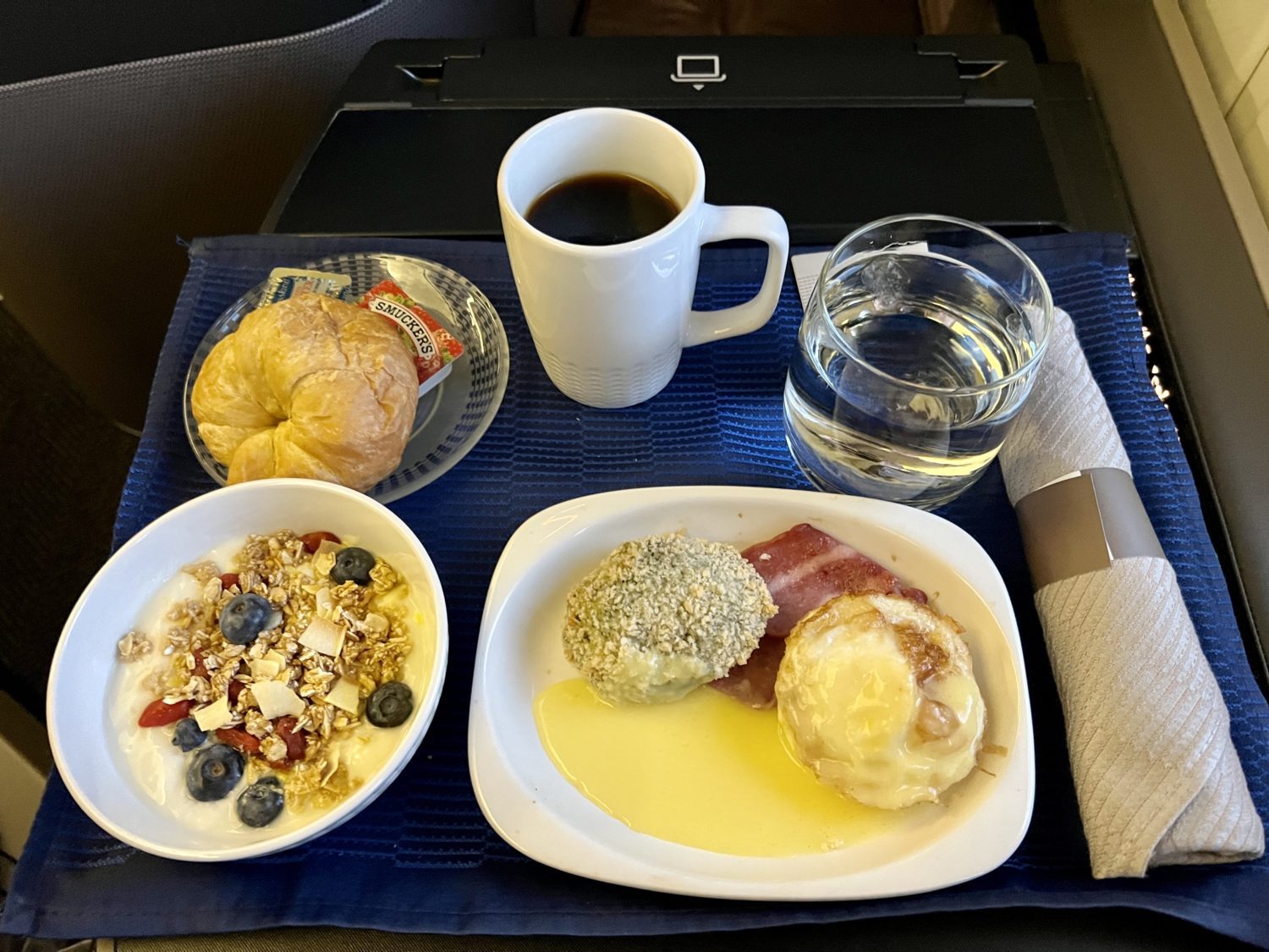eggs with yogurt parfait and coffee on a plane tray