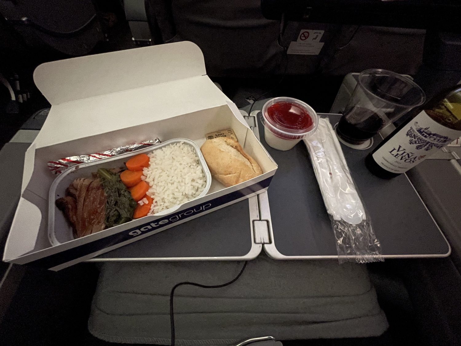 a boxed meal of chicken and rice on an airplane tray table