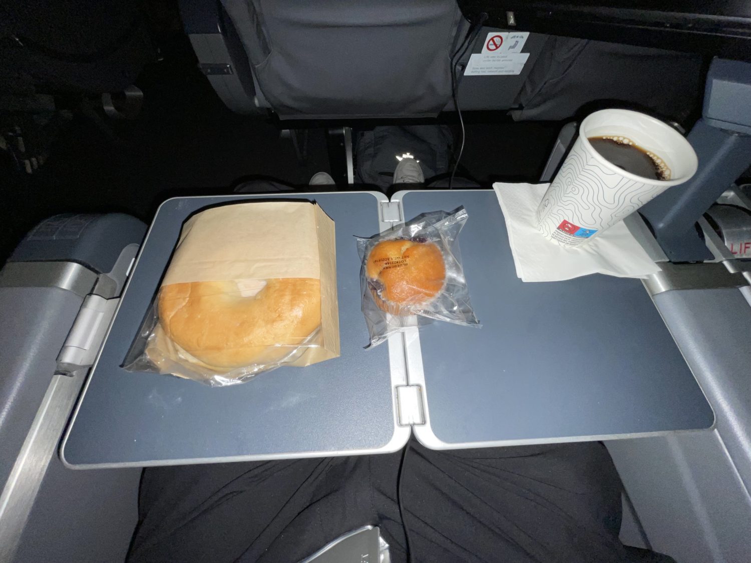 bagel, muffin and coffee on an airplane tray