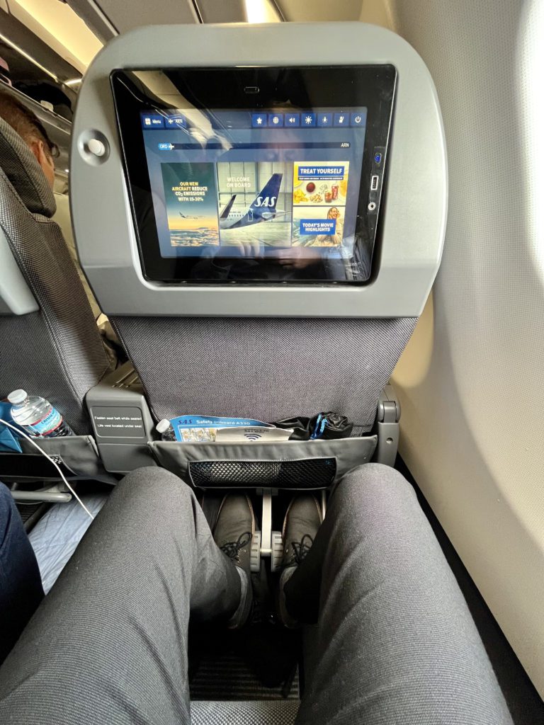 a man's legs in a premium economy airplane seat