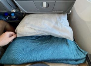 A pillow and blue blanket given to travelers on an economy flight