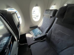 an economy airplane seat fully reclined in front of a bright window. 