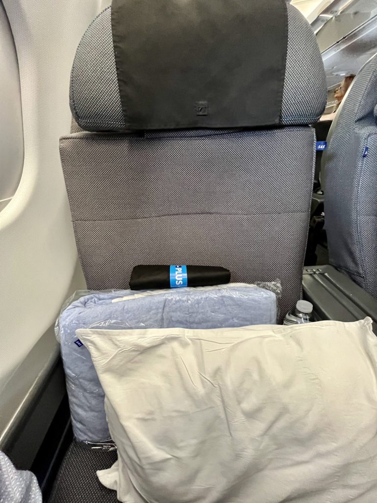 pillow and blanket sitting on an airplane seat